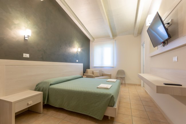 Camera con letto matrimoniale, TV a muro e finestra.