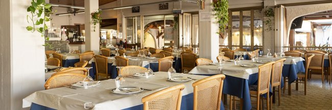 Sala ristorante con tavoli apparecchiati.