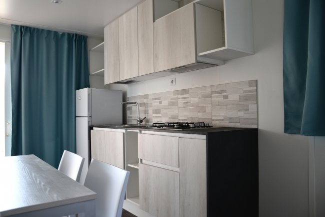 Cucina moderna con mobili chiari e tendine blu.