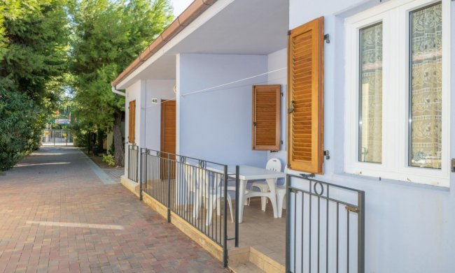 Una casetta blu con sedie bianche sul portico.