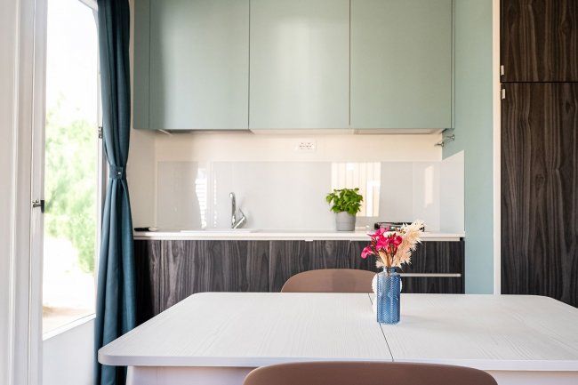 Cucina moderna con tavolo e fiori in vaso.