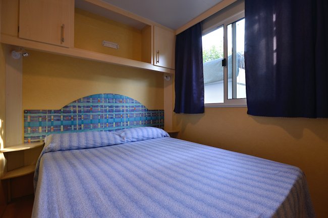 Camera con letto matrimoniale e copriletto blu a righe.