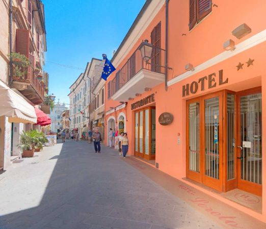 Una strada pedonale con hotel e ristoranti, persone che passeggiano.