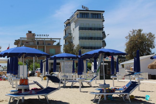 Ombrelloni blu e lettini su una spiaggia sabbiosa.