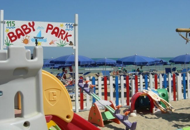 Area giochi per bambini sulla spiaggia, con ombrelloni blu.