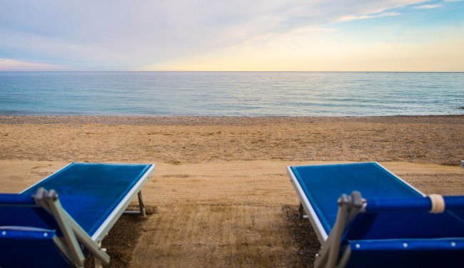 Due lettini blu fronte mare al tramonto.