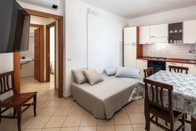 Interno luminoso con angolo cucina e divano letto.