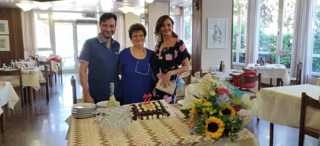 Tre persone con una torta di compleanno in un ristorante.