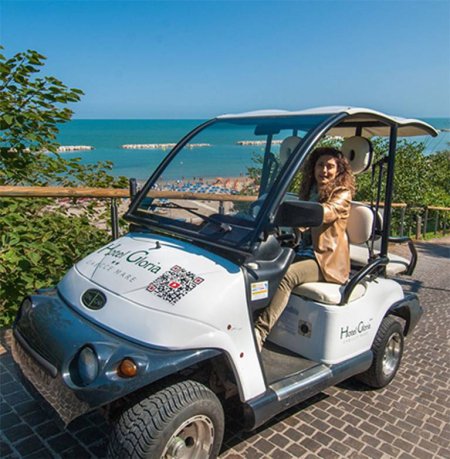 Persona in una golf car bianca vicino alla spiaggia.