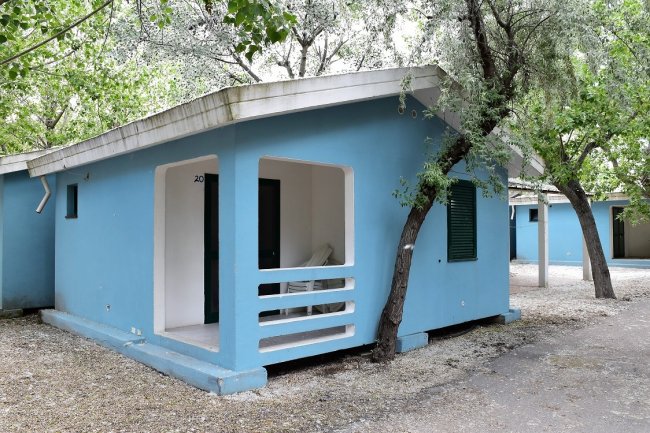 Bungalow blu con veranda aperta e sedia bianca.