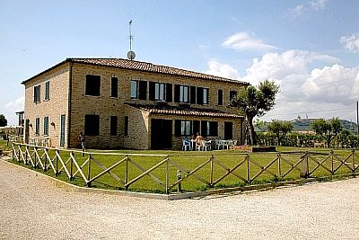 Una casa a due piani con persiane verdi, un ampio prato e un recinto di legno.