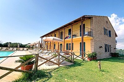 Un edificio giallo con balconi e ombrelloni vicino a una piscina.