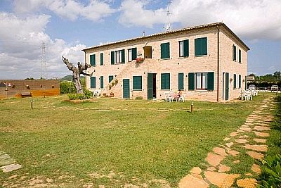 Una casa in mattoni con persiane verdi, circondata da un giardino e un vialetto di pietre.