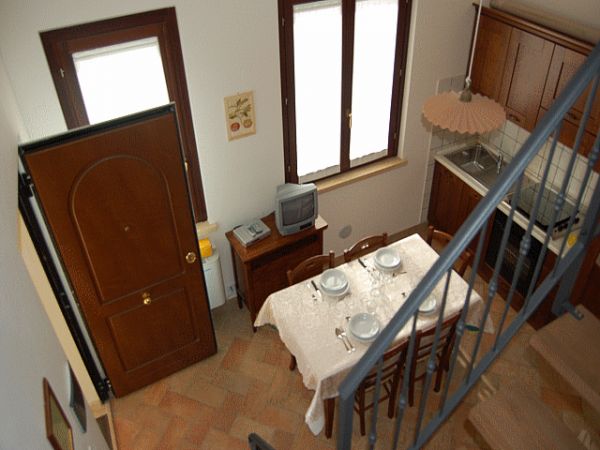 Vista dall'alto di una cucina con tavolo apparecchiato e TV piccola.