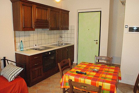 Cucina con mobili in legno e tavolo con tovaglia a quadri colorati.