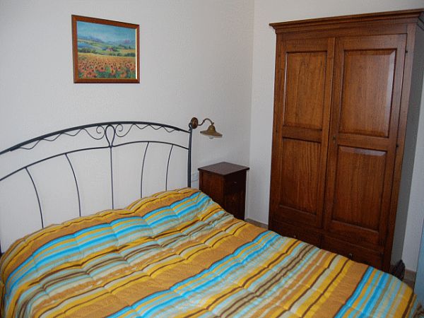 Camera con letto matrimoniale, copriletto a righe, comodini e armadio in legno.