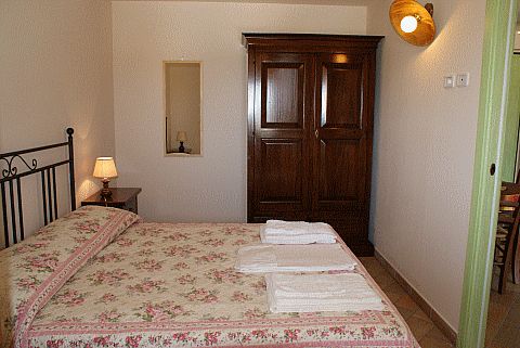 Camera da letto con letto matrimoniale, copriletto floreale, armadio in legno e lampada da comodino.