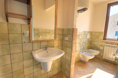 Bagno con lavabo, bidet e water; pareti con piastrelle verde pastello.
