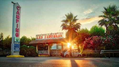 Ingresso campeggio con palme al tramonto.