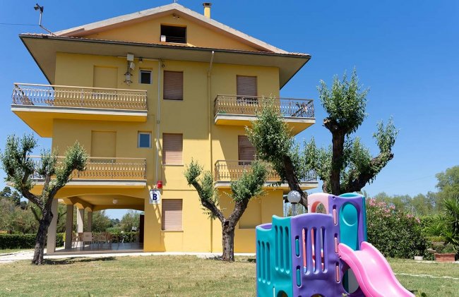 Edificio giallo con scivolo nel giardino.