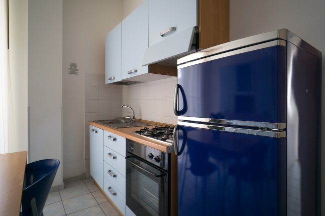 Cucina con frigorifero blu e mobili bianchi.