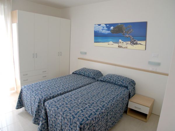 Camera con letti singoli e quadro di spiaggia.