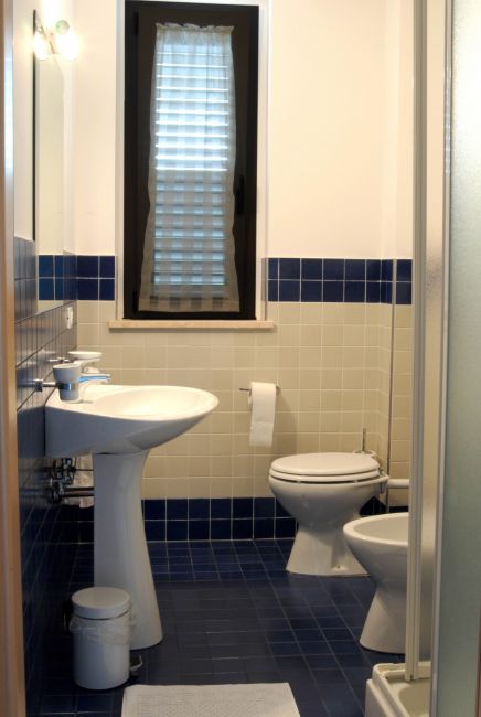 Bagno con lavabo, wc e finestra con tenda a rullo.