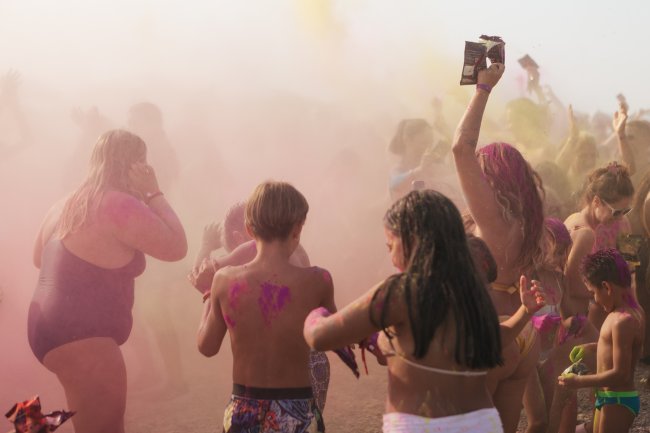 Un gruppo di persone danza tra polveri colorate.