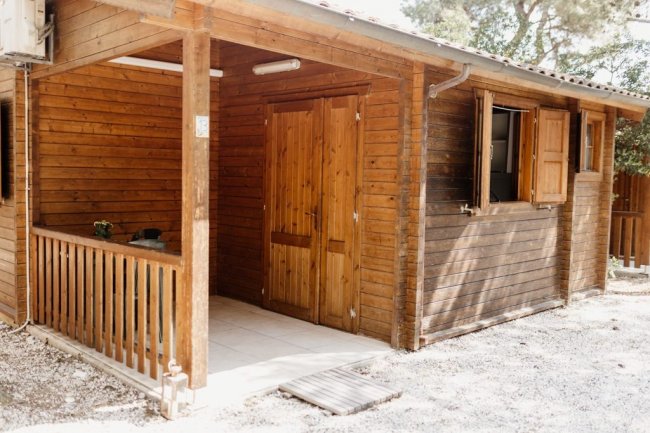 Casetta di legno con portico e finestre aperte.