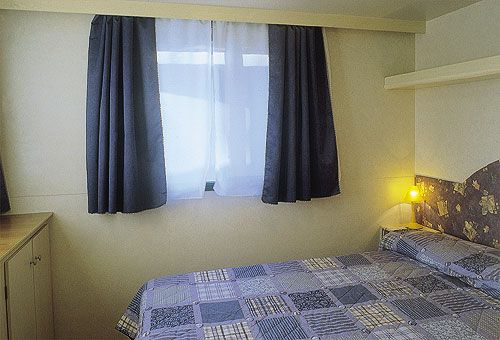 Camera da letto con letto matrimoniale, coperte a quadri e tende scure.